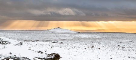 Golden sunrays over snow covered Great Links Tor, Dartmoor